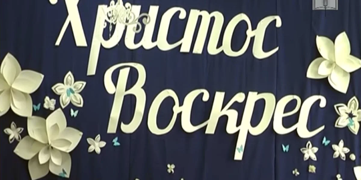 Синя стіна залу з написом «Христос Воскрес» і паперовими квітами
